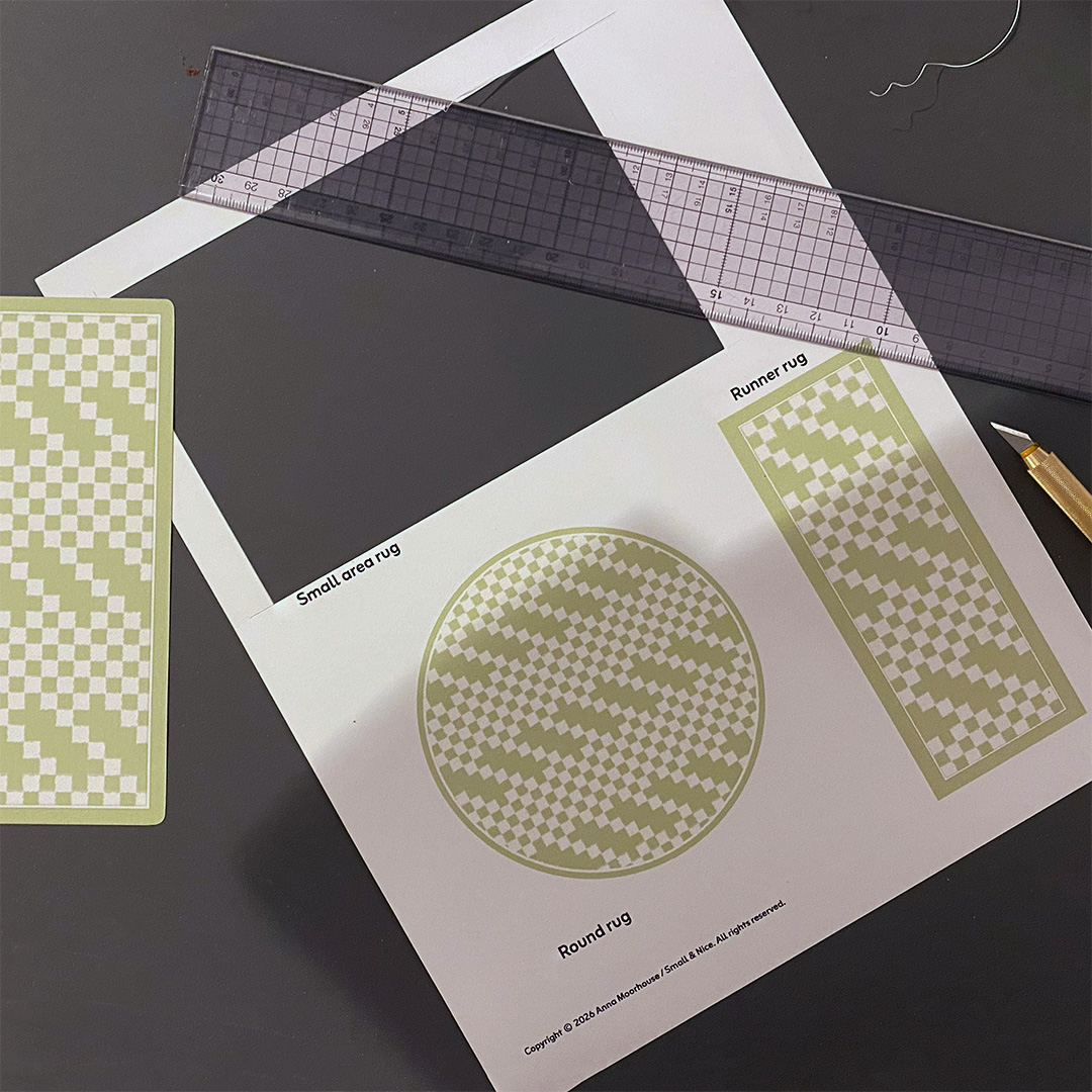 a piece of paper a ruler and a craft knife with a mini rug cut out of the paper