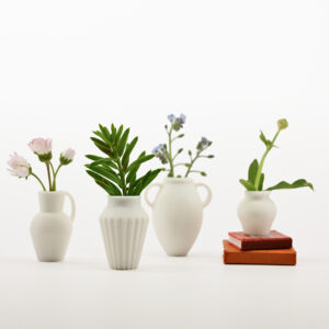 Four tiny vases in a row with greenery