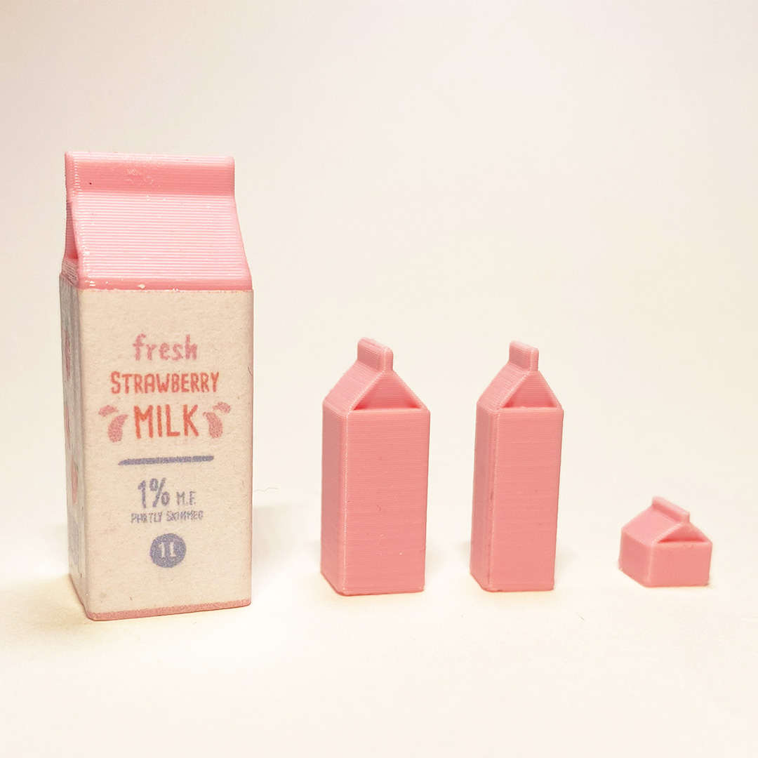 Mini milk cartons in pink with a label attached to the largest