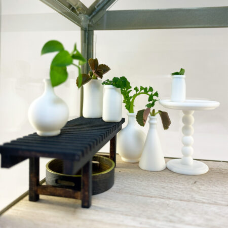 a photo of tiny white vases in a mini greenhouse